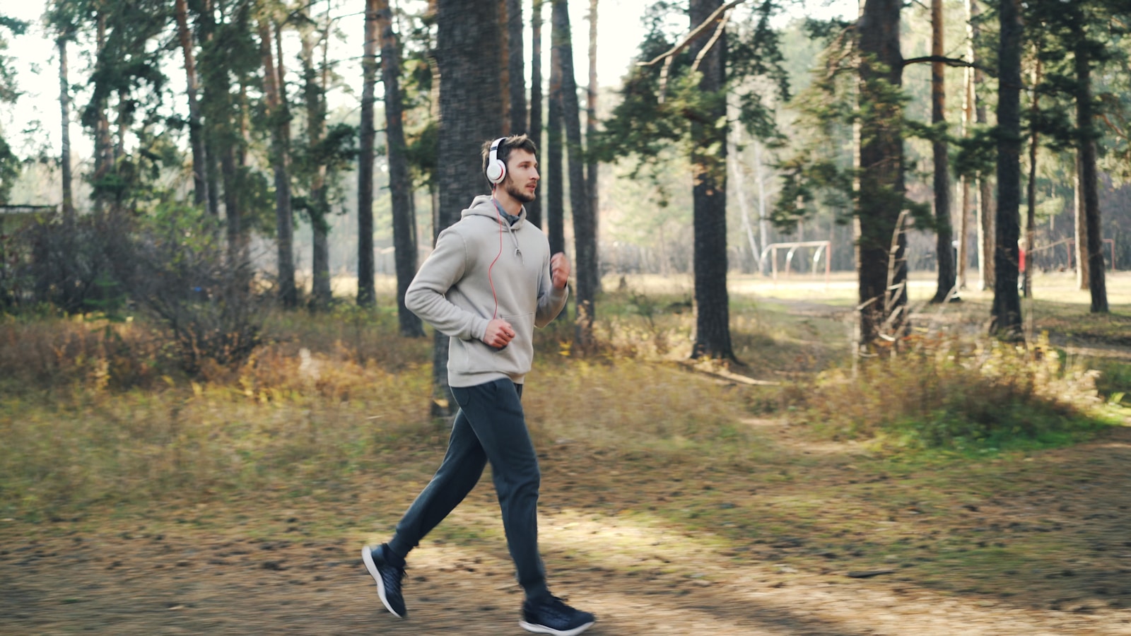 Man running in a forest with headphones on.